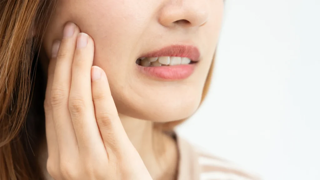 Woman touching her cheek due to tooth sensitivity, representing common dental discomfort caused by Hyderabad’s climate and temperature changes.